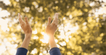 Woman reaching towards sky in prayer